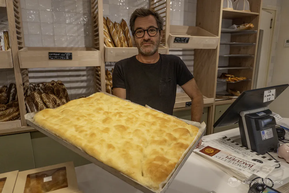Boulanger montrant une fougasse fraîchement sortie du four, dans une boulangerie artisanale du centre. Photo par diegoenfrance.com
