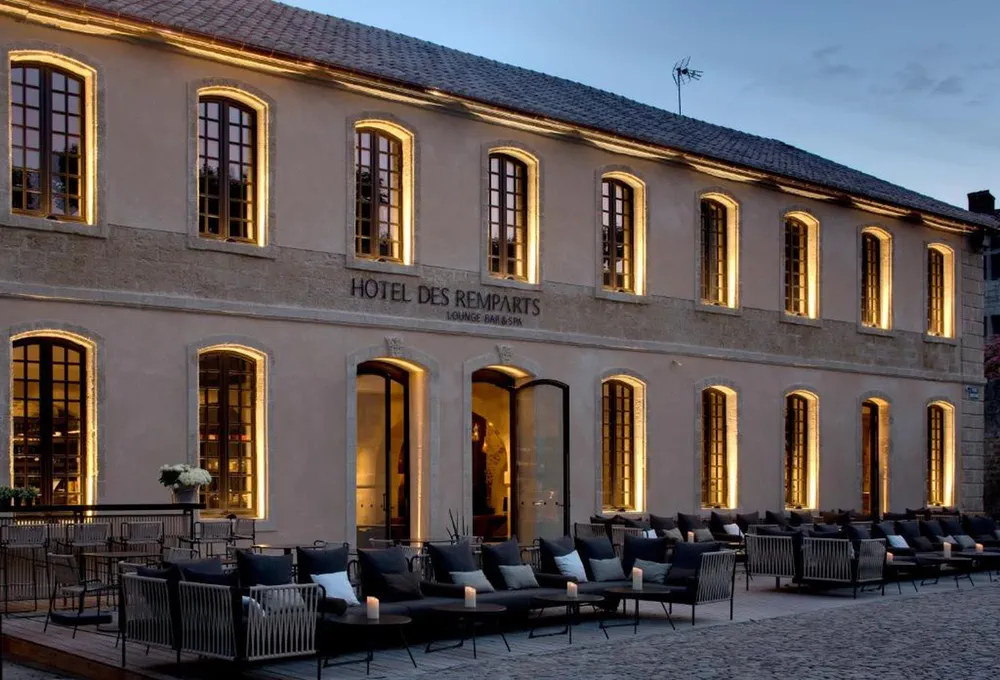 Façade illuminée au crépuscule de l'Hôtel des Remparts, un refuge sophistiqué dans le centre historique.