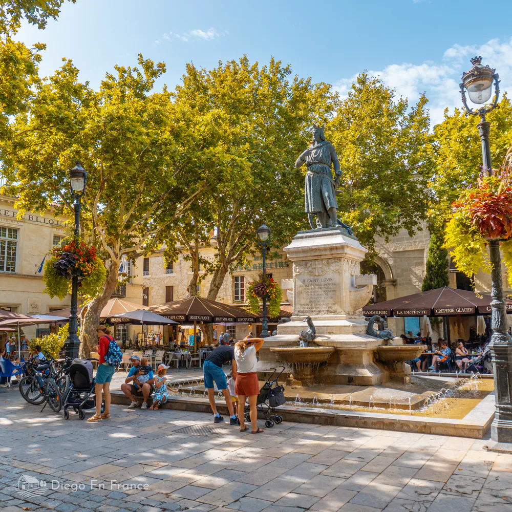 Photographie de diegoenfrance.com : fontaine centrale et ambiance familiale sur la place Saint-Louis, point clé d’Aigues-Mortes.