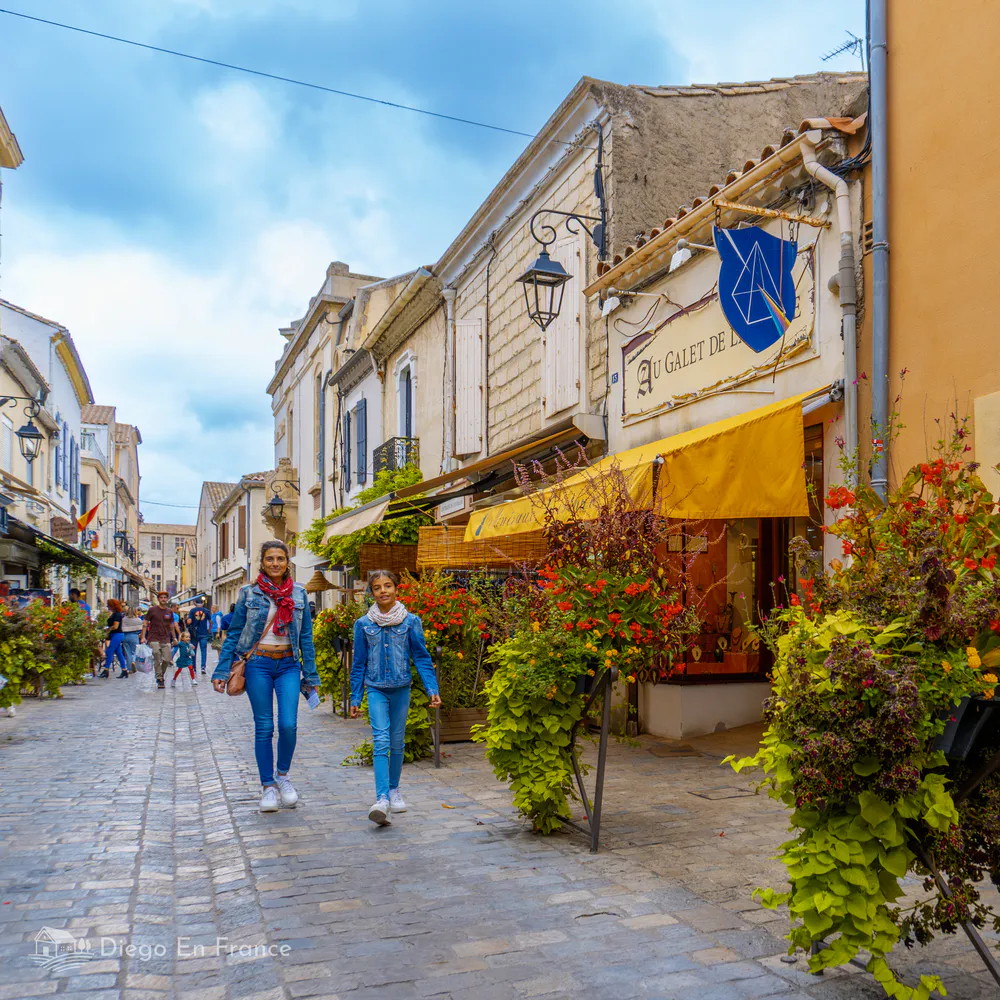 Rue piétonne colorée, commerces locaux et animation dans le centre historique d’Aigues-Mortes. Photographie de diegoenfrance.com