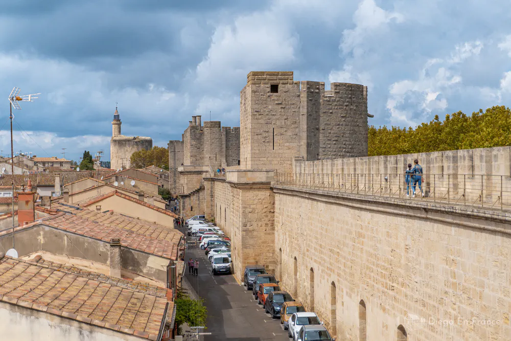 Photographie de diegoenfrance.com : touristes marchant sur les remparts d’Aigues-Mortes avec vue sur les toits.