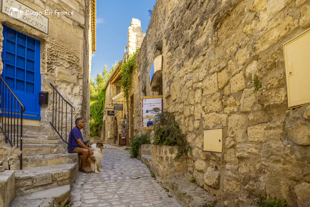 Fotografía de diegoenfrance.com de habitante con su perro en calle de piedra de Les Baux-de-Provence, ejemplo de turismo slow en pueblo medieval