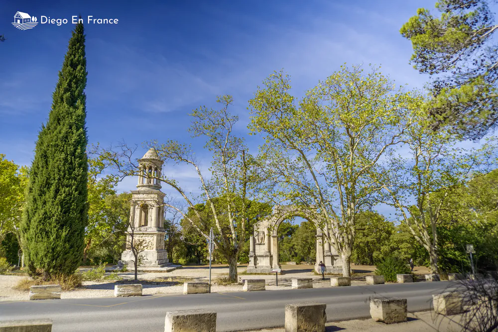 Fotografía de diegoenfrance.com del mausoleo y arco triunfal de la ciudad antigua de Glanum rodeados de cipreses y plátanos