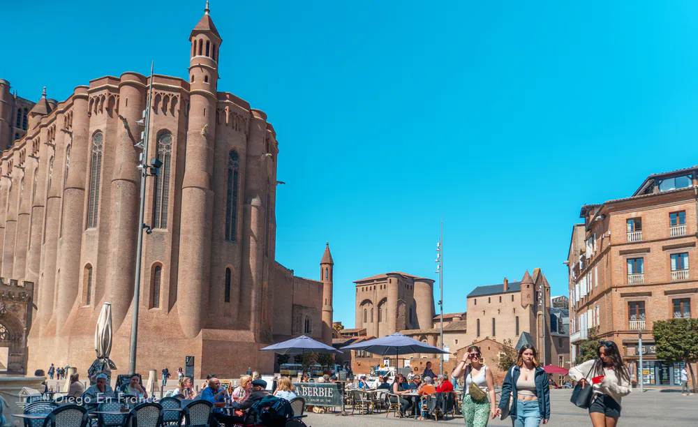 Place devant la cathédrale Sainte-Cécile d'Albi, avec des terrasses et une ambiance animée.