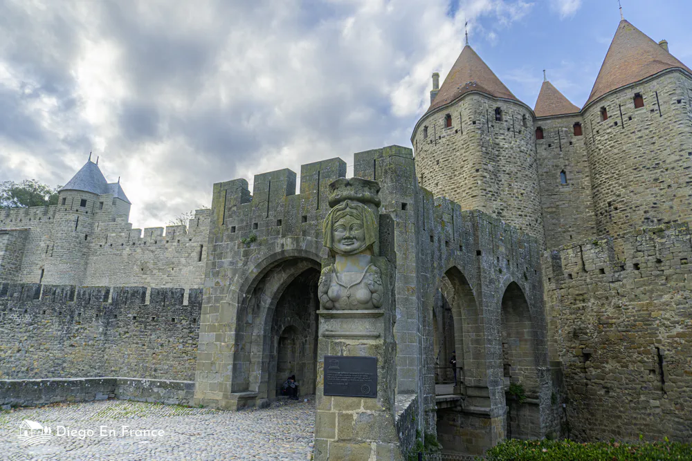 Puerta principal fortificada de Carcasona con esculturas y murallas, símbolo histórico del turismo familiar en la región