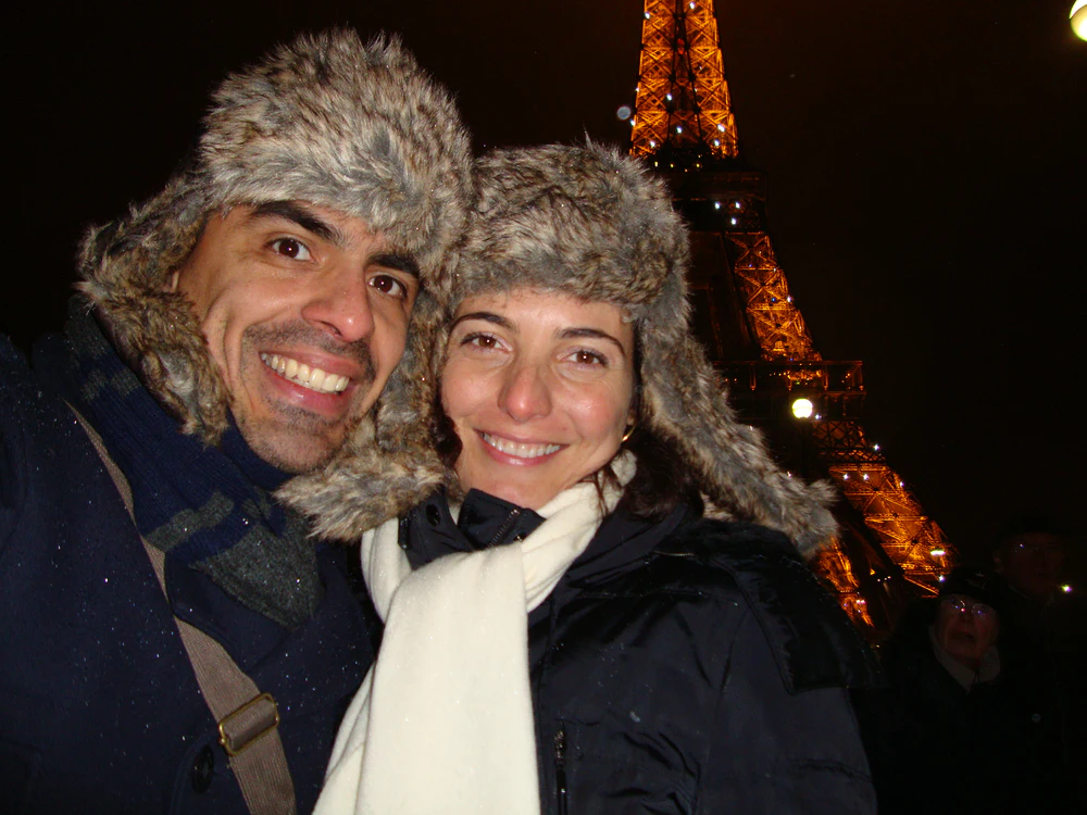 Una pareja feliz y sonriente en Paris con la Tour Eiffel iluminada de fondo