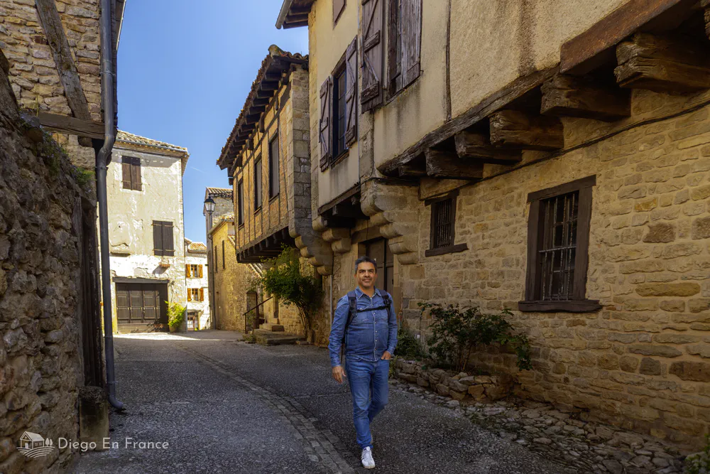 Tourist walking through the stone streets of Puycelsi, ideal for an excursion of history and landscapes from Toulouse. Photo by diegoenfrance.com 