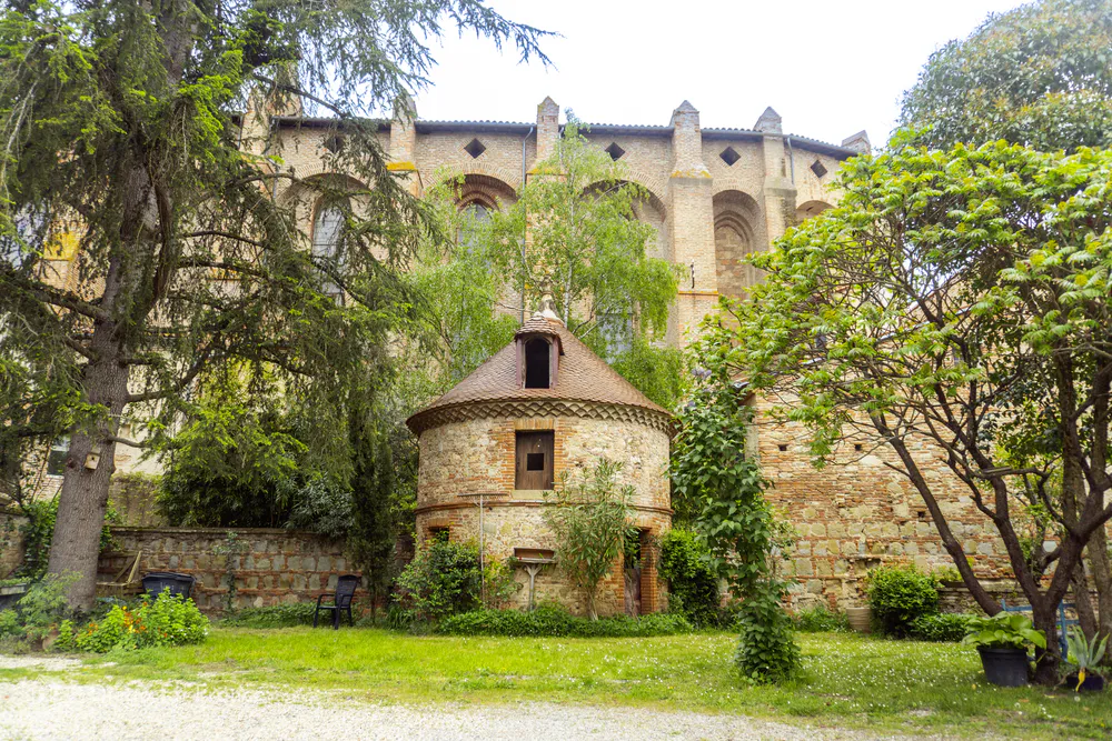 Green space behind the Saint-François de Lavaur church, with trees and brick architecture, ideal for those looking for charming corners near Toulouse. Photo by diegoenfrance.com
