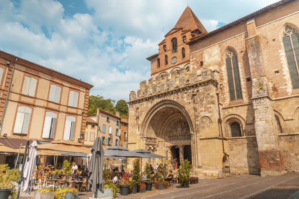Facade of the abbey of Saint-Pierre in Moissac with its Romanesque architecture and lively terraces, perfect for a quiet excursion from Toulouse. Photo by diegoenfrance.com
