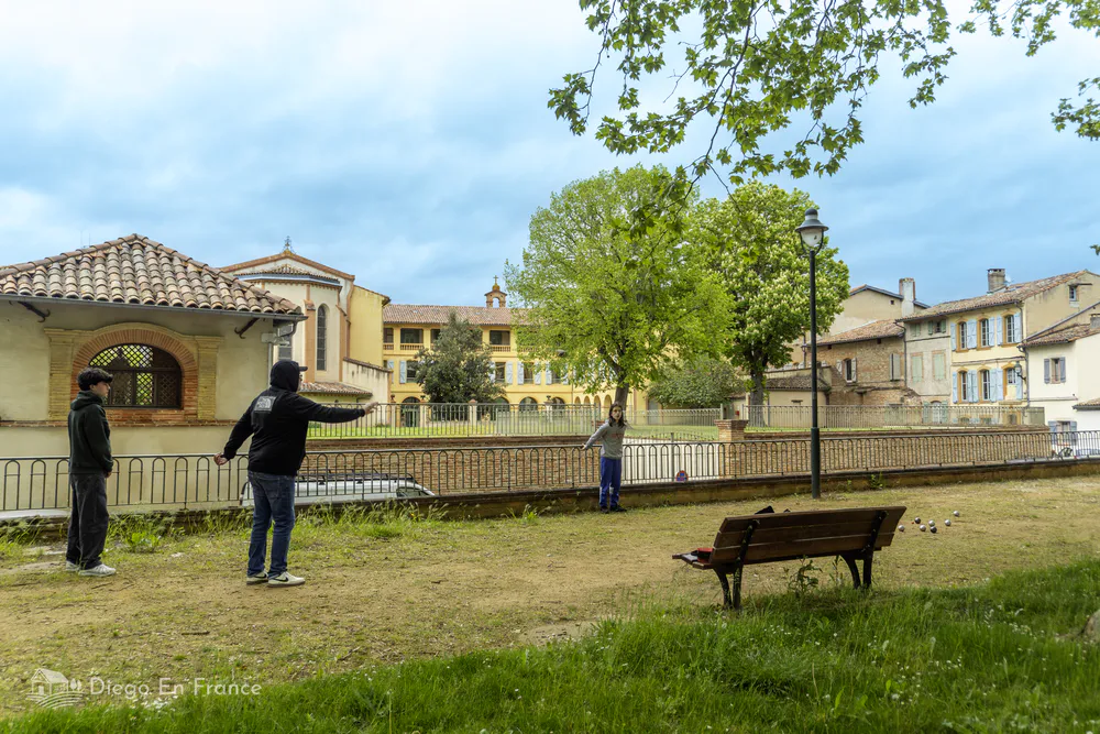 Scene of an urban park in Lavaur where locals enjoy a game of petanque.