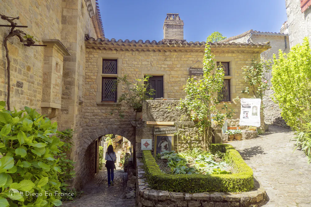 Woman entering a narrow passage under a medieval house in Bruniquel’s historic district.