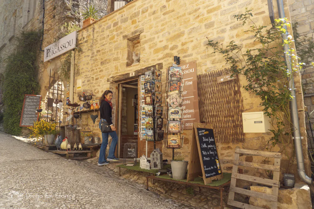 Woman entering a small boutique selling crafts, souvenirs, and local specialties in Bruniquel.