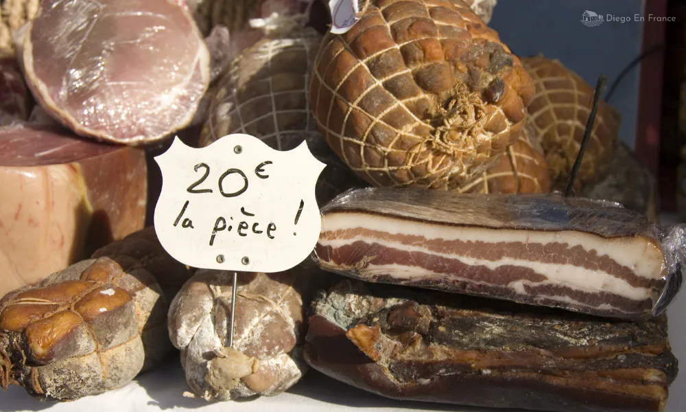 Close-up of traditional cured pork products with price tag at a farmer’s market in Bruniquel.