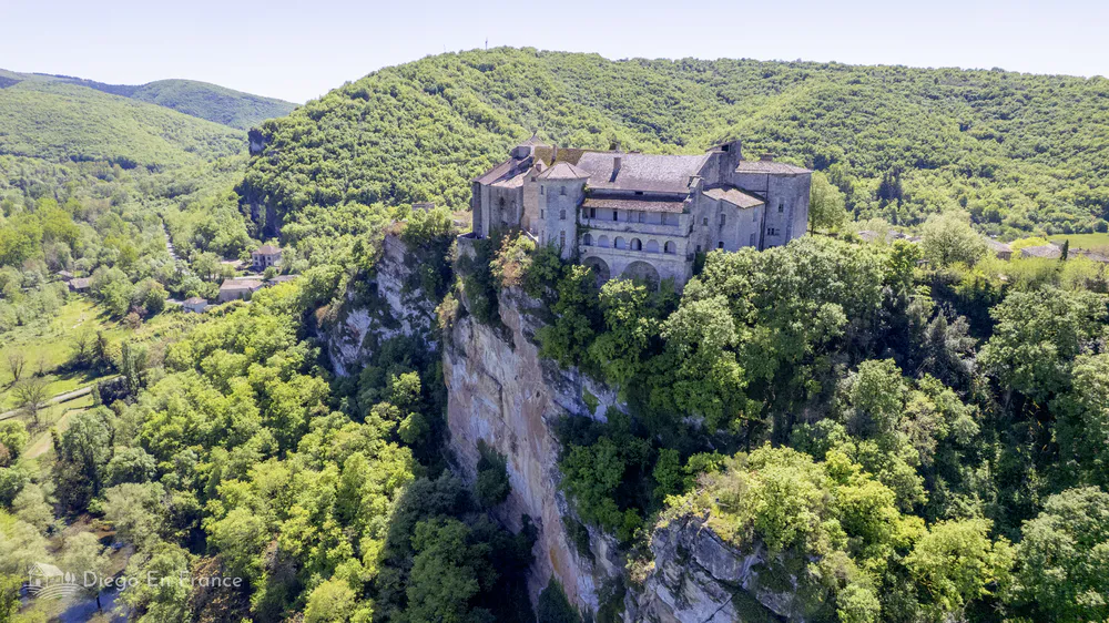 Drone view of the Château de Bruniquel sitting dramatically on a limestone cliff in Occitanie.