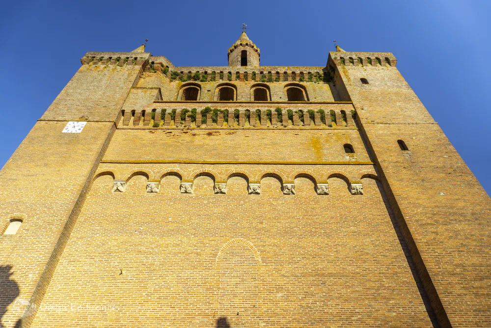 Gothic church of Saint-Sulpice-la-Pointe seen from below, with brick walls and imposing tower.