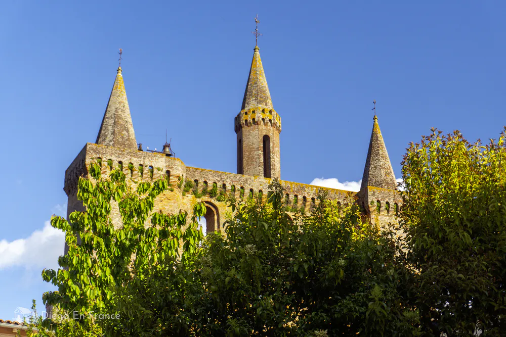 Detail of the Gothic towers of the Église Saint-Sulpice seen from a garden with blue sky.