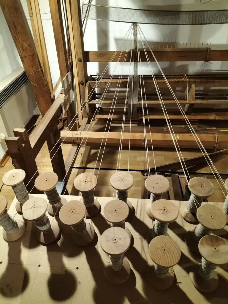 Detalle de un telar de madera con bobinas de hilo natural, ejemplo del saber hacer artesanal del pueblo.