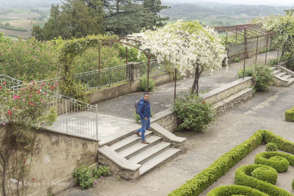 Visitante en el jardín municipal de Lautrec, rodeado de flores y vistas al campo.