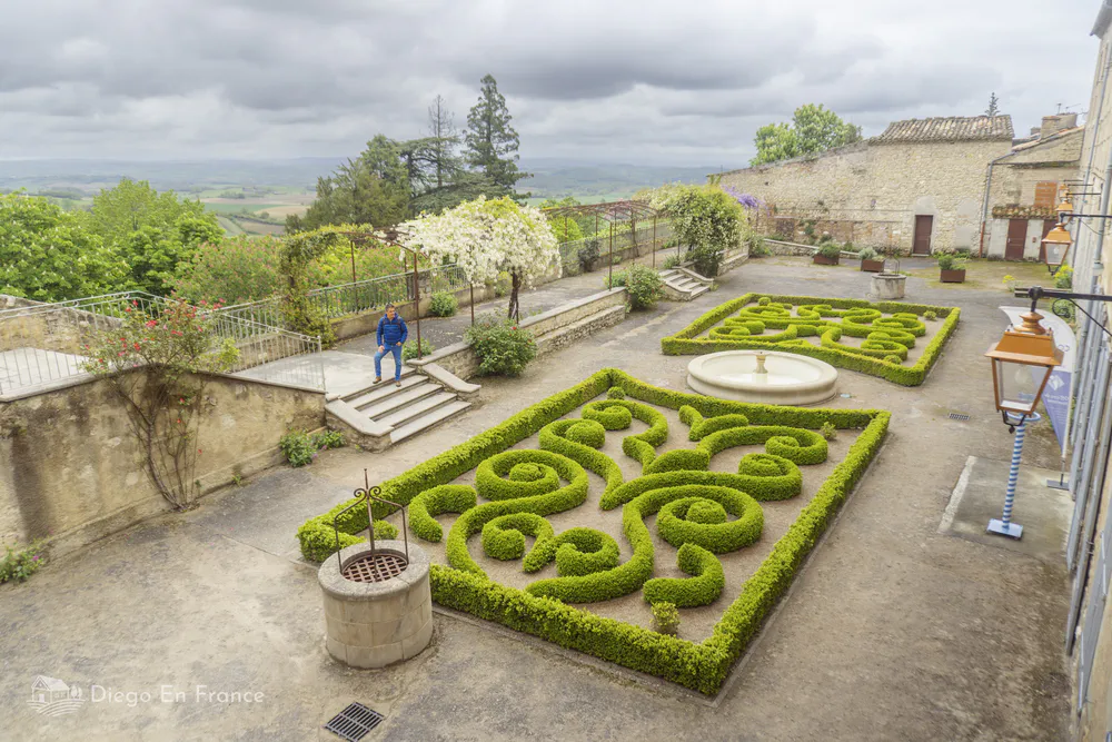 Vista del jardín público de Lautrec con setos recortados y una fuente central, ideal para descansar.