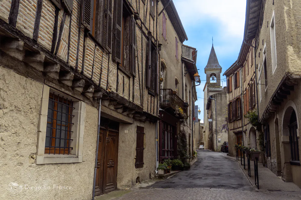 Arquitectura tradicional en una calle medieval de Lautrec, con su iglesia como punto focal.