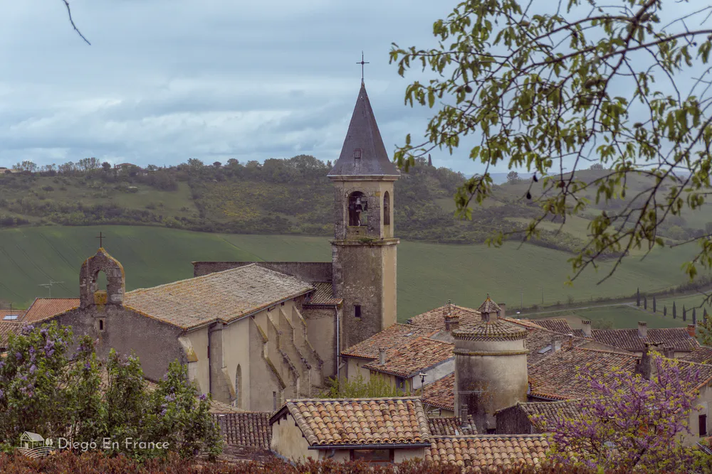 Vista pintoresca de la iglesia de Lautrec desde un mirador natural entre árboles.