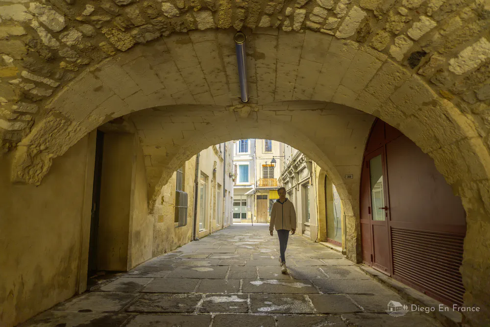 Rue voûtée en pierre au cœur de la vieille ville de Lunel, idéale pour les promenades historiques. Photo par diegoenfrance.com