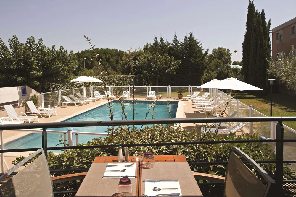 Hôtel Mon Auberge à Lunel, avec restaurant et piscine entourée de verdure.