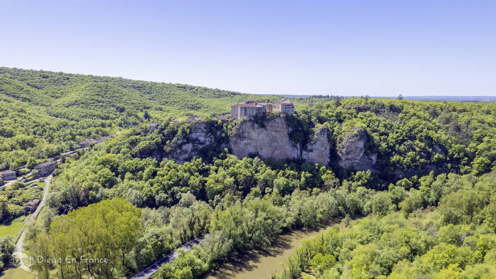 Wide aerial shot of Bruniquel’s cliffside castles above the forested Aveyron Valley in southwest France.