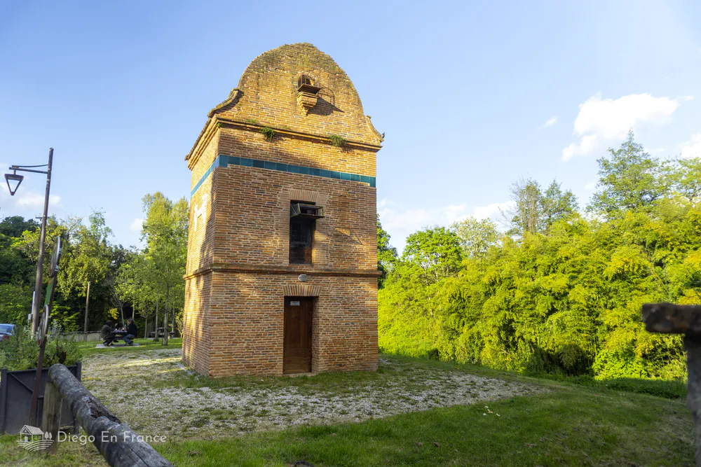 Old red brick dovecote in Saint-Sulpice-la-Pointe with clear skies and natural surroundings.