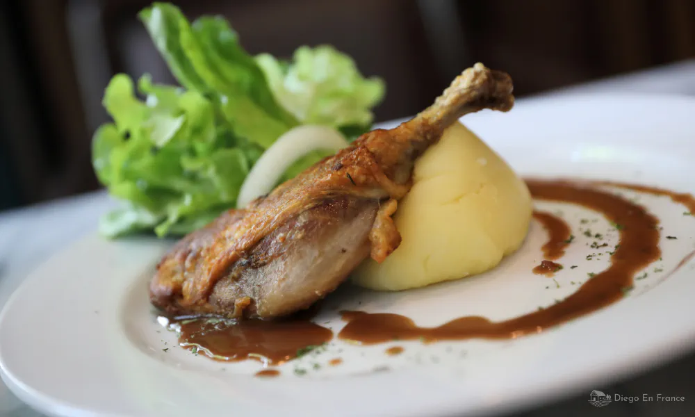 Close-up of a traditional duck confit dish served with creamy mashed potatoes in Bruniquel.
