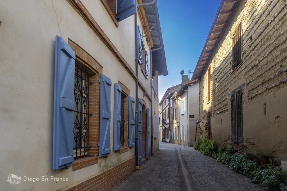 Traditional architecture of Saint-Sulpice-la-Pointe with painted wooden shuttered windows.