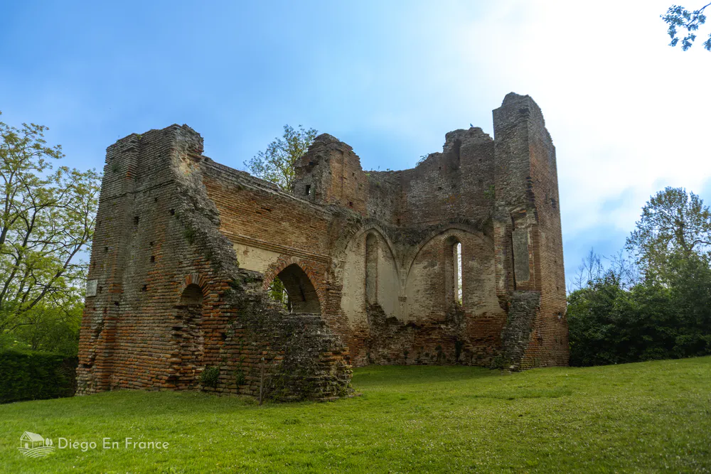 Remains of medieval fortification in Saint-Sulpice-la-Pointe, surrounded by lawns and trees.