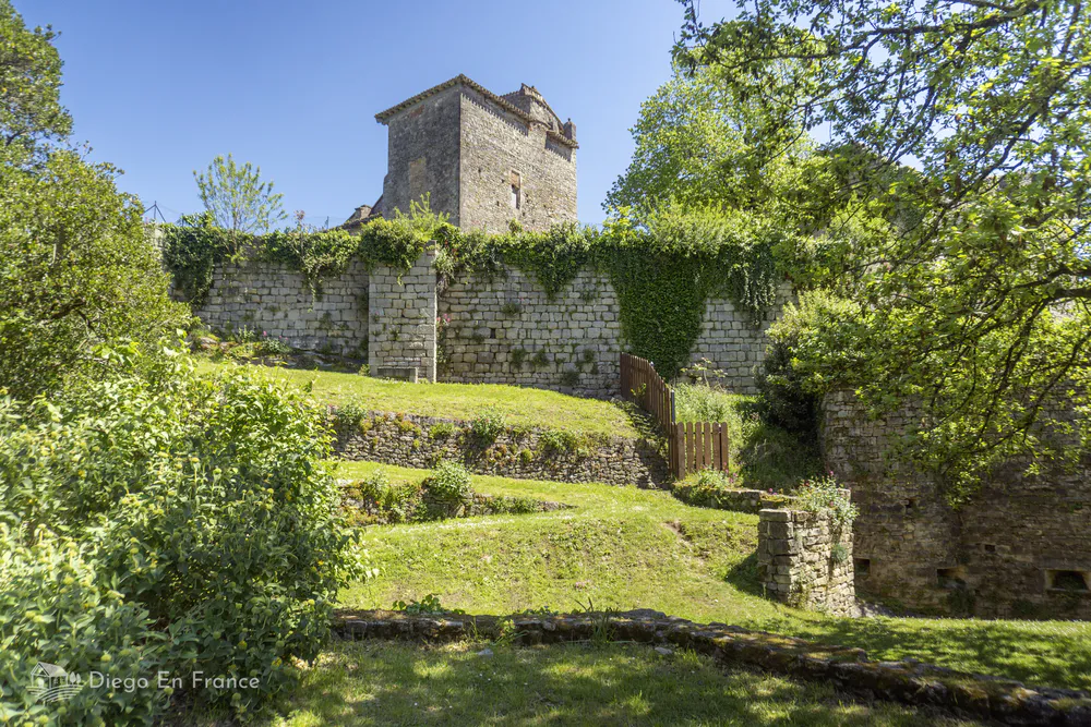 Grassy picnic area with stone walls and castle ruins in the upper gardens of Bruniquel.